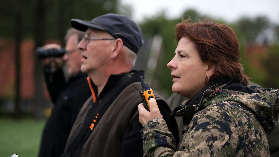 Erika Elsjan van WBE instrueert met een portofoon de loper in het perceel over de plek waar een warmteplek is gesignaleerd. De loper probeert zoveel mogelijk langs de kant van het perceel te gaan om het lange gras te sparen. Soms gebeurt het dat er een ha