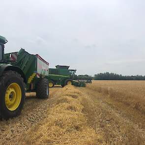 De overslagwagen staat achter een John Deere, ook de combine is van John Deere.